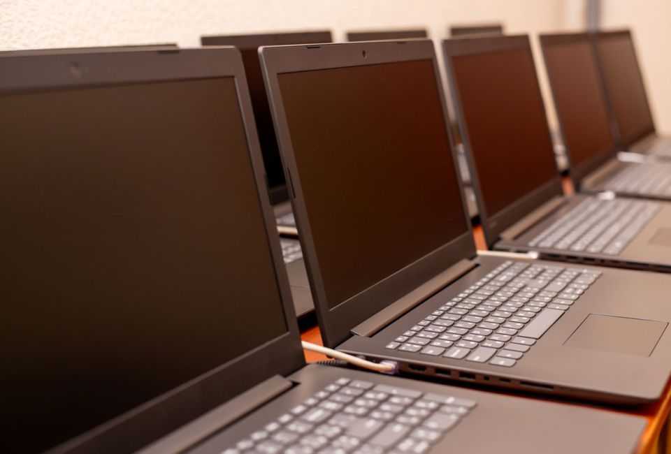 A row of black laptops neatly arranged on a table, showcasing their sleek design and uniform appearance.