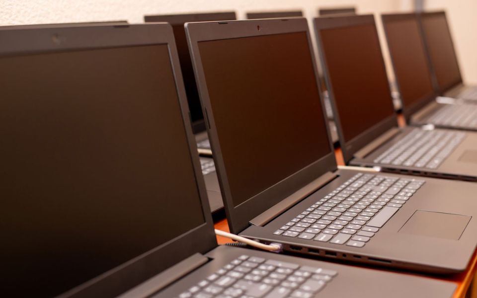 A row of black laptops neatly arranged on a table, showcasing their sleek design and uniform appearance.